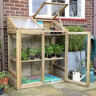 Small wooden mini greenhouse in a UK garden – one of the top 10 small greenhouses and polytunnels UK 2025.