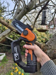 Worx WG324E review showing the mini chainsaw cutting a branch in a UK garden