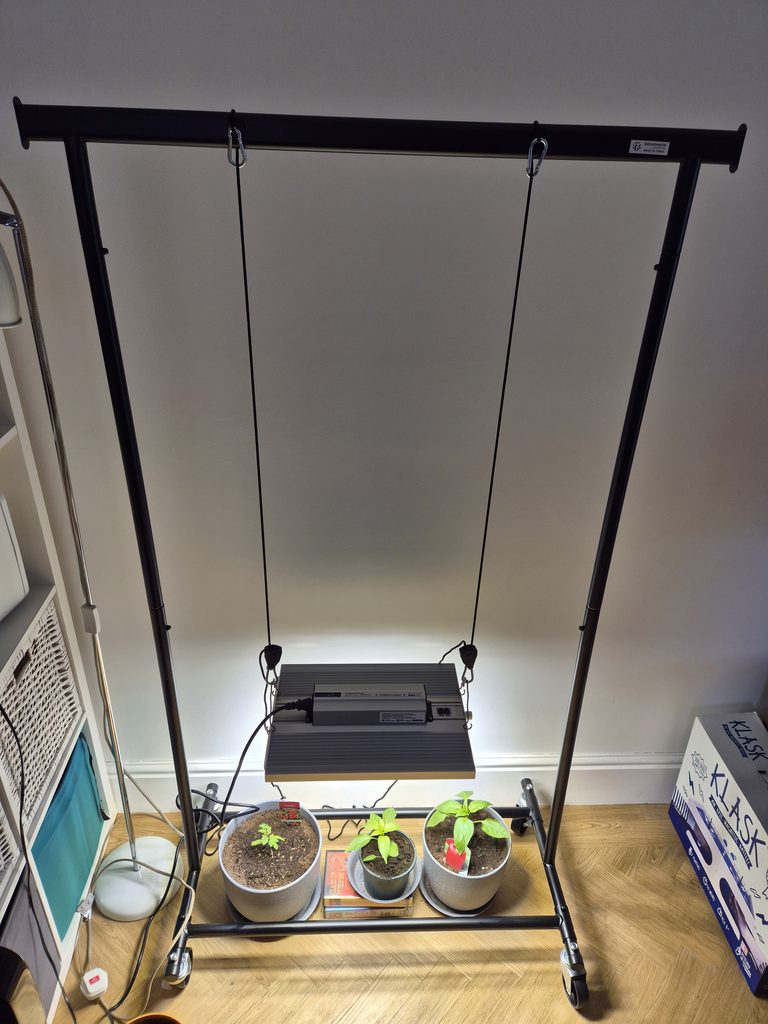 ViparSpectra XS1500 Pro review hanging from a freestanding clothes rail above three young indoor plants
